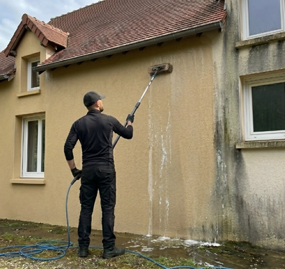Nettoyage de façade en crépi à Tours — artisan Eauxigen en intervention softwash sur maison rurale en Val de Loire, balai télescopique sur enduit jaune ocre, coulures de produit visibles, méthode douce sans pression agressive, Mars 2026