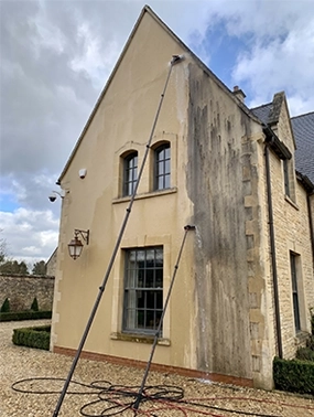 Nettoyage de façade au softwash en Val de Loire — perche télescopique à eau pure Eauxigen sur une maison en pierre, fort contraste avant/après, méthode douce basse pression sans abîmer l'enduit