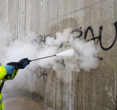 Nettoyage de graffitis et tags sur mur en béton à Vendôme — vapeur basse pression Eauxigen avec lance projetant de la vapeur sur peinture noire, effacement progressif sans abrasion du support, Val de Loire