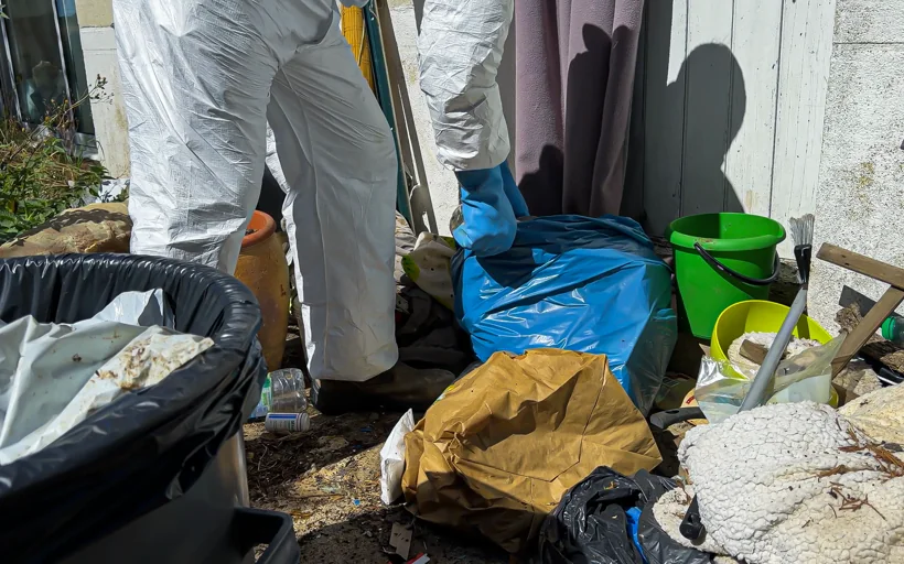 Intervenant Eauxigen débarrassant les déchets accumulés à l’extérieur d’un logement