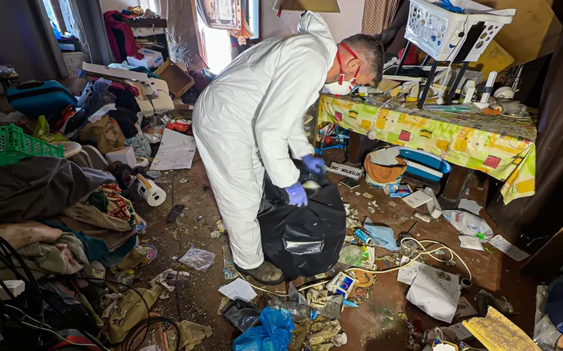 Intervenant Eauxigen triant et mettant en sac les déchets d’un logement très encombré